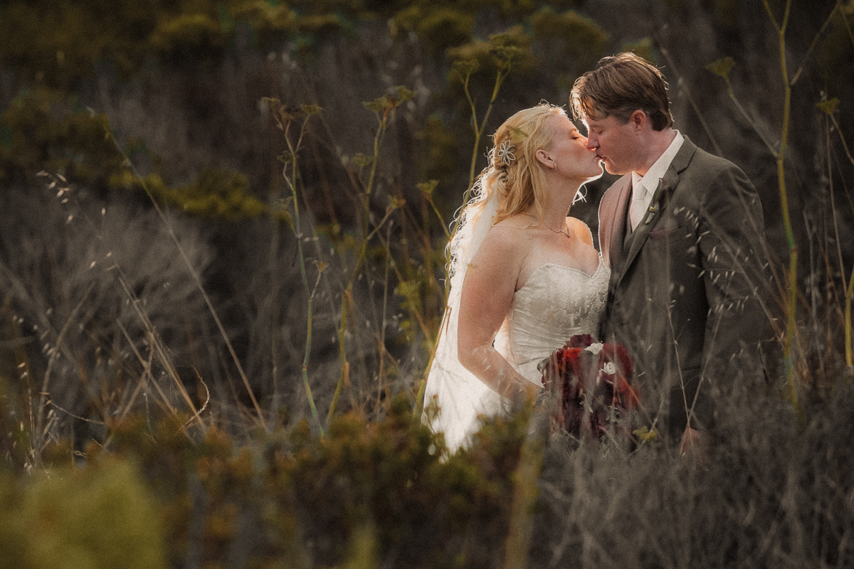 bride and groom sharing a romantic kiss on a Santa Cruz beach during their California wedding