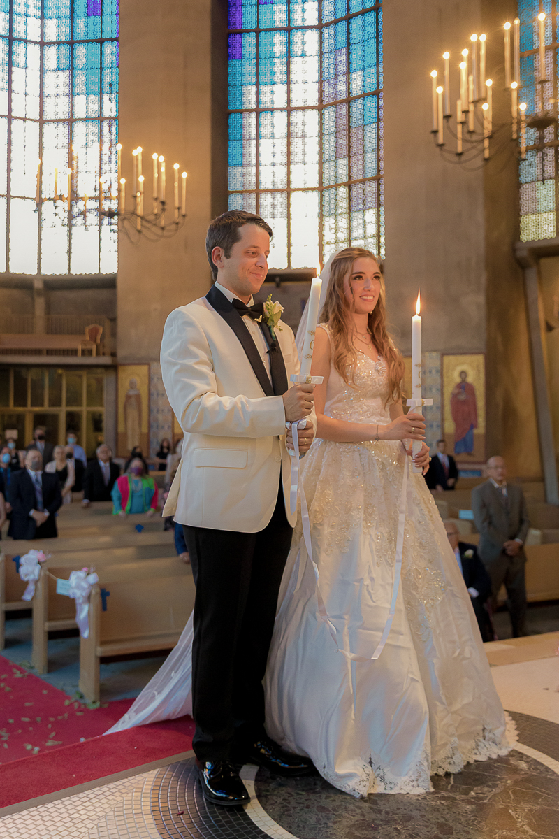 bride and groom holding candles at the altar during their wedding at Holy Trinity Greek Orthodox Church in San Francisco