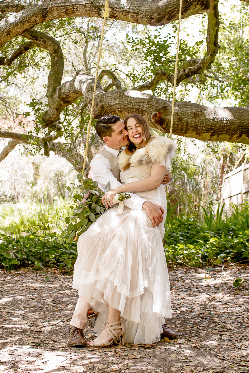 bride and groom laughing together on a swing at their Park Winters wedding in California