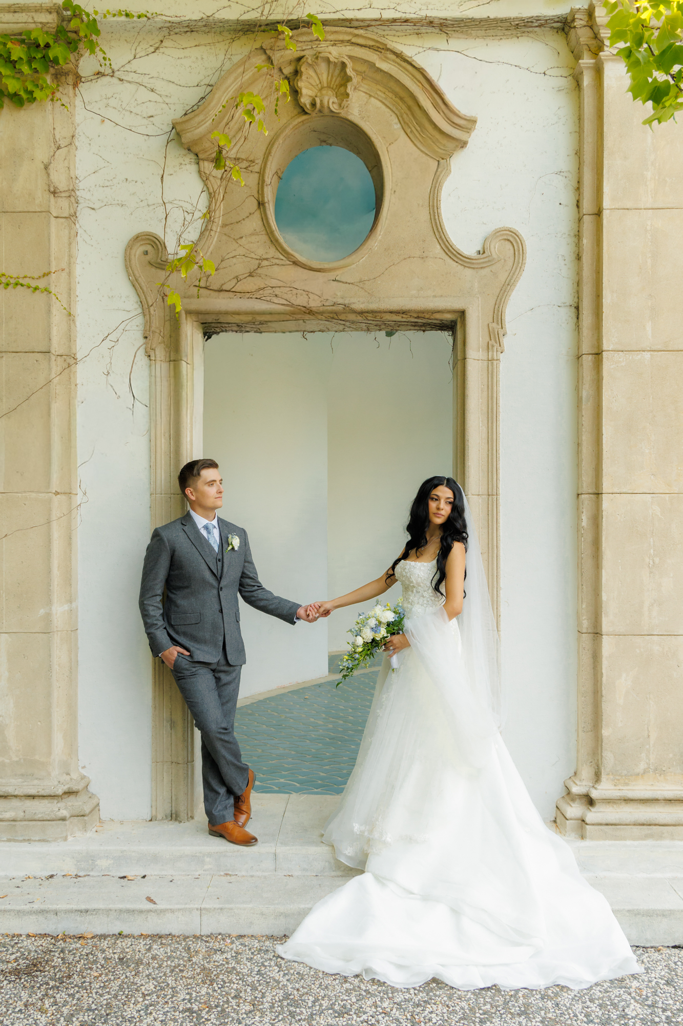 Bride and groom holding hands in stone archway at Hacienda de las Flores wedding venue in Moraga California