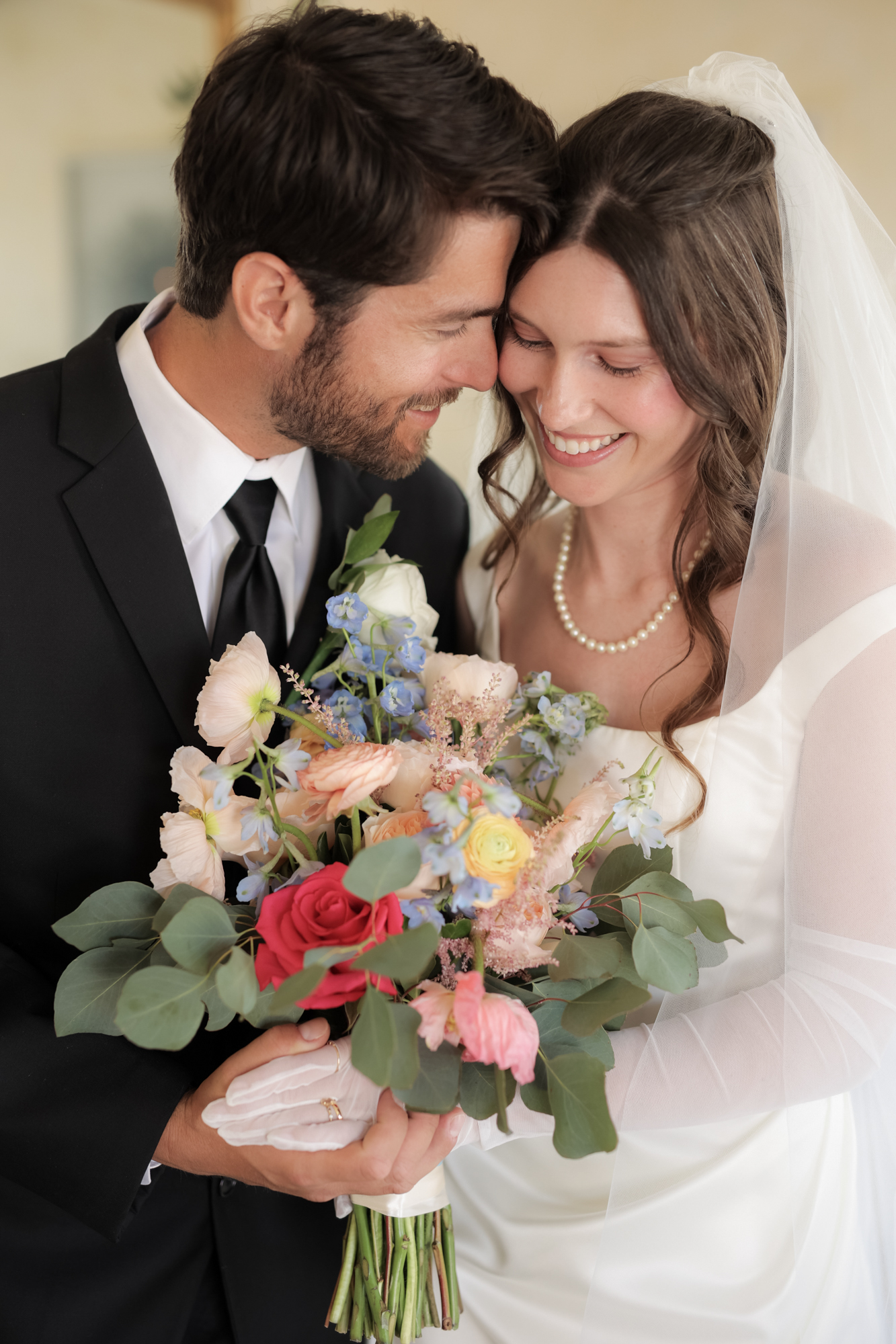 Bride and groom smiling together holding colorful bouquet at The Barns at Cooper Molera wedding in Monterey California