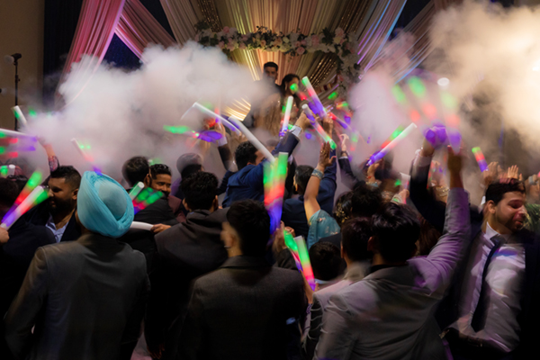 Guests celebrating with glow sticks during energetic wedding reception at White Lotus Banquet Hall