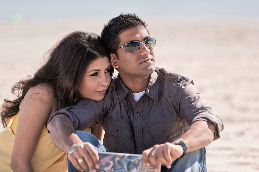 romantic engaged couple enjoying a quiet moment together on the sand reading a book at baker beach san francisco