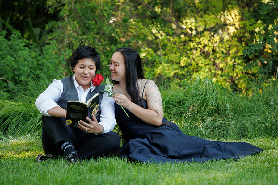 romantic lgbtq couple enjoying a poetic moment together on the grass with a rose during napa valley engagement session