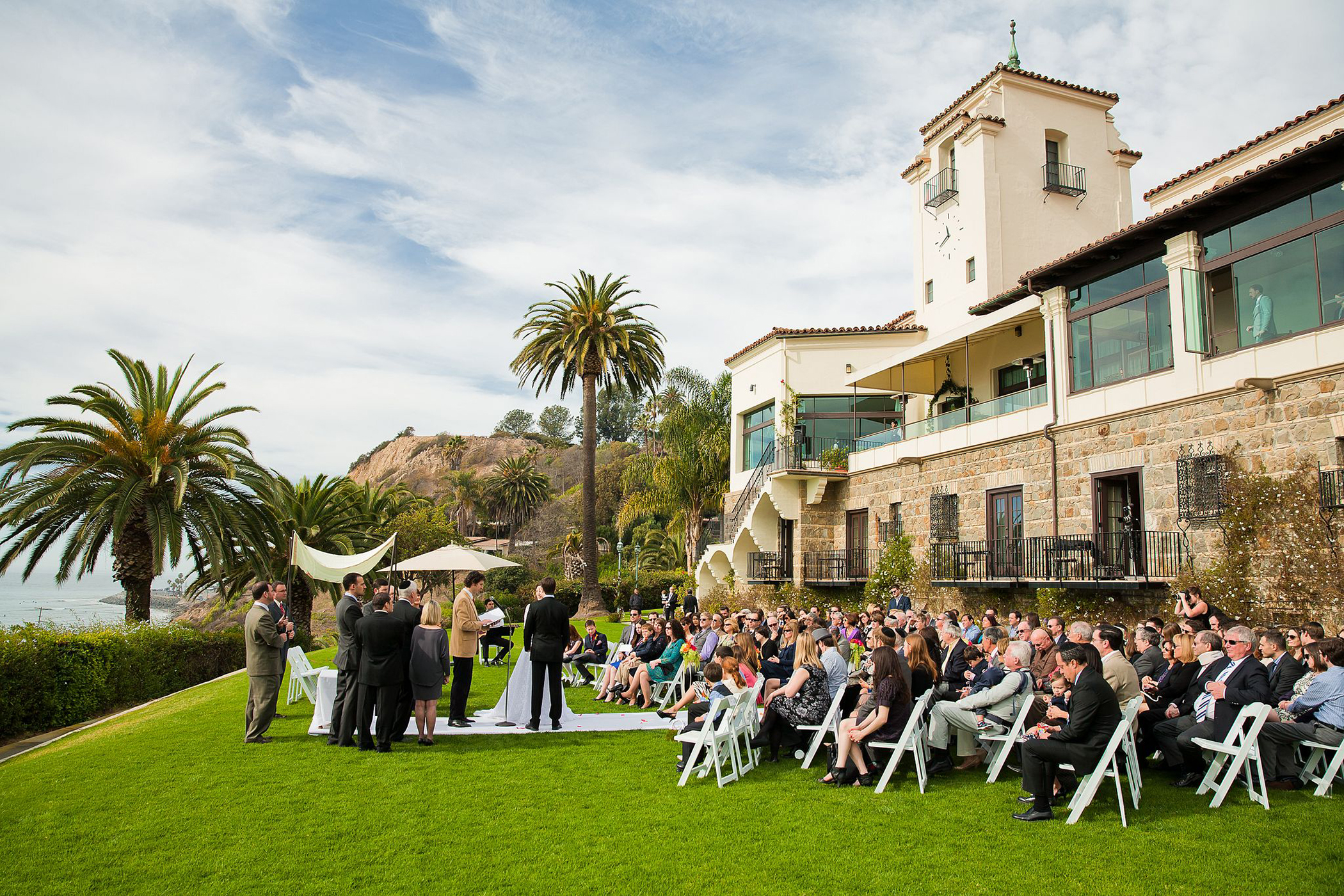 Wide view of an elegant wedding ceremony at Bel-Air Bay Club with ocean views and guests gathered along the California coast