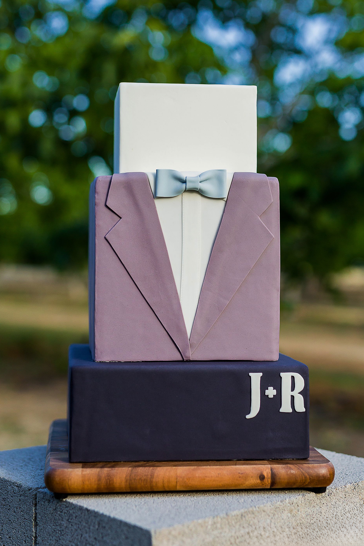 Elegant wedding cake decorated with a bow tie at a same-sex wedding reception filled with celebration and pride.