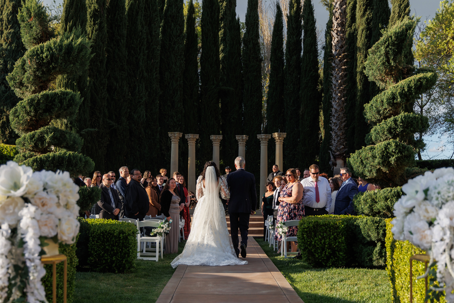 Bride walking down the aisle with her parents during a wedding ceremony at Grand Island Mansion