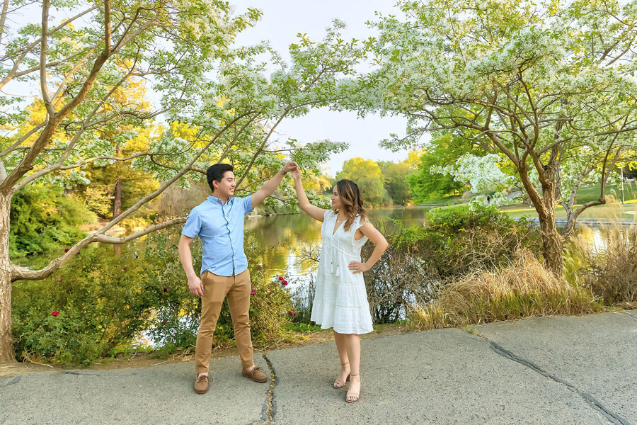 Couple in UC Davis Arboretum surrounded by greenery, the lake, soft light and fun candid moment