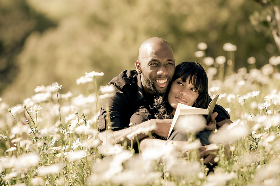 Couple reading together in white flowers at golden hour, soft natural light and quiet romantic moment in bloom