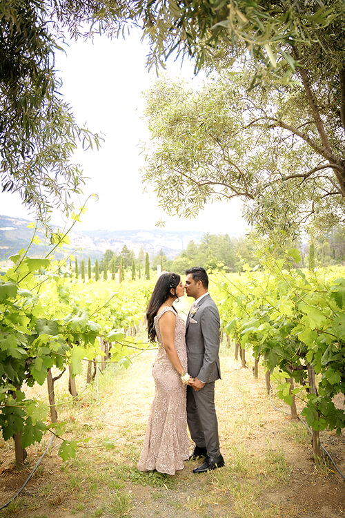 Romantic engagement photo in vineyard at Castello di Amorosa Napa Valley with couple among vines in golden light