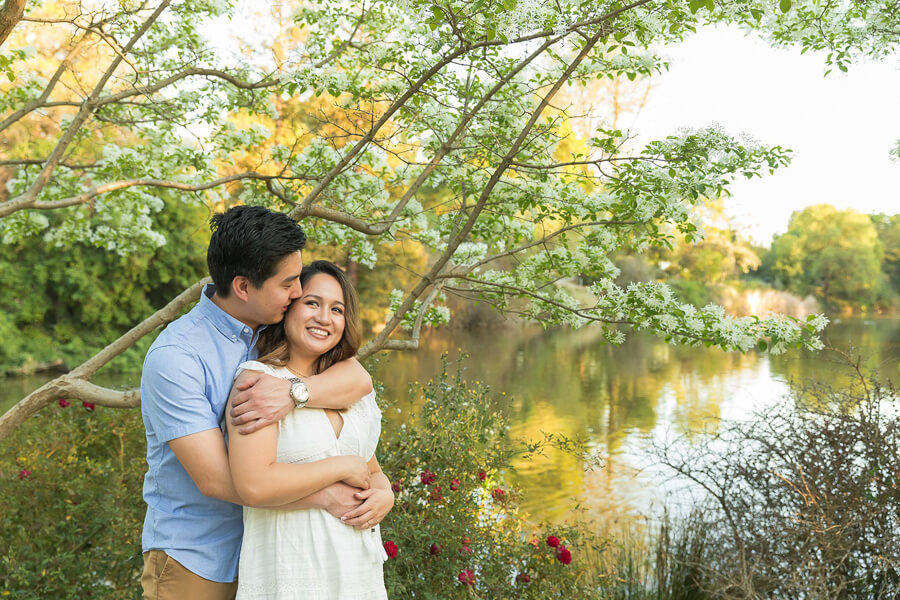 Couple by the lake at UC Davis Arboretum, calm water reflections and soft natural light with relaxed romantic moment