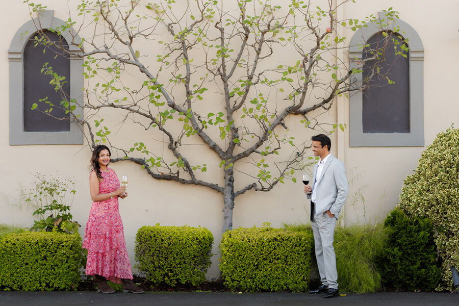 Couple laughing and enjoying wine at Beringer Winery in Napa Valley, candid playful engagement moment in warm light