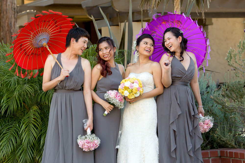 Bridesmaids laughing together with colorful umbrellas during fun wedding moment at Boundary Oak Golf Course in Walnut Creek California
