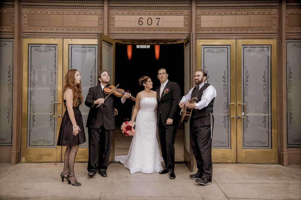 Bride and groom being serenaded by a live band in downtown Sacramento during their wedding celebration.