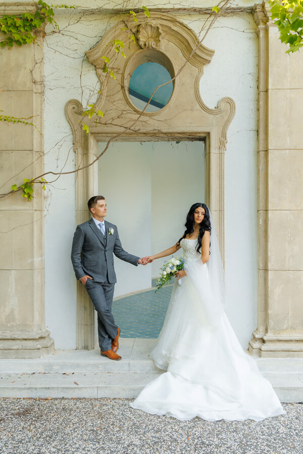 Classic bride and groom portrait beside the grand columns at Hacienda de las Flores wedding venue