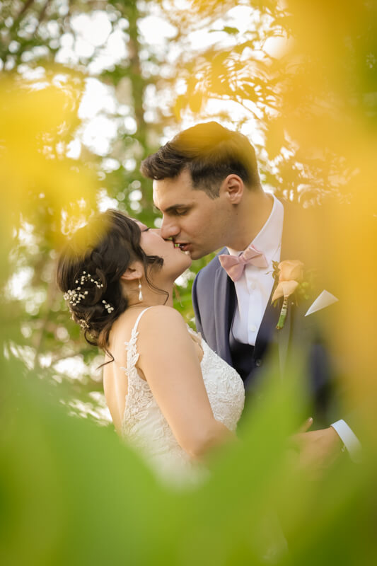 Bride and groom sharing a romantic kiss framed by flowers at Vizcaya Sacramento during their wedding
