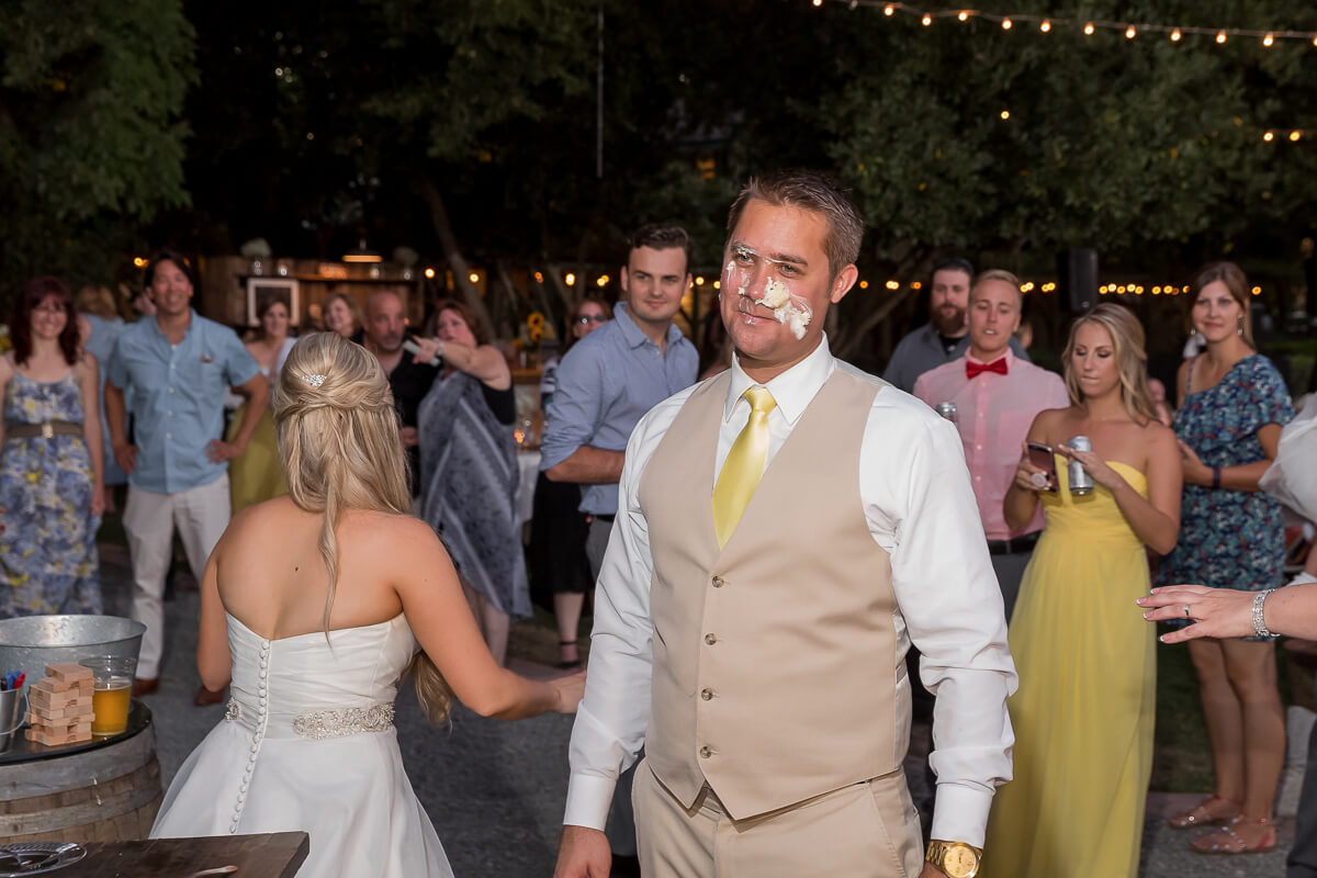 Bride playfully smearing cake on the groom's face at Yolanda Ranch.